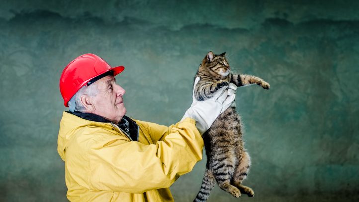 Old man in safety suit holds cat with his arms